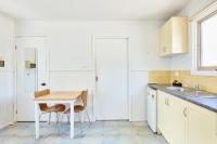 a white kitchen with a wooden table and chairs at Lorne Foreshore Caravan Park in Lorne