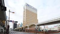 Un edificio alto en una calle de la ciudad con un puente. en Toyoko Inn Iwakuni eki Nishi guchi, en Iwakuni