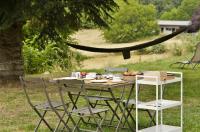 a table with chairs and a plate of food on it at Une pause en Corrèze in Sarroux