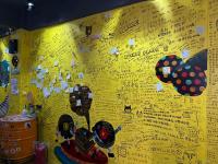 a yellow wall with many stickers on it at Hive Bed and Backpacker蜂巢膠囊旅店 in Hualien City