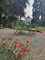 two chairs and a table in a garden with red flowers at LES 5 ESCALES in Parthenay