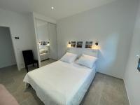 a white bedroom with a bed and a chair at Villa de standing in Calvi