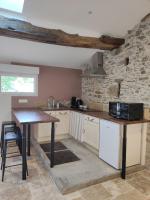 a kitchen with white cabinets and a wooden table at Studio 30m2 La Cave - Les Gîtes du Lac - Proche Nantes in La Chevrolière