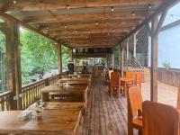 Un restaurante con mesas y sillas de madera en una terraza. en Barlogul din Vidraru, en Curtea de Argeş