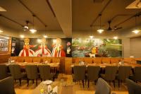 a restaurant with tables and chairs and a large painting at Hotel Dolphin Grand in Varanasi