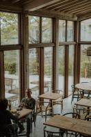 un uomo seduto ai tavoli in una stanza con finestre di Borgo 69 Villas & Suites a Foiano della Chiana