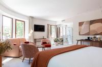 a bedroom with a bed and chairs and a television at La Bastide Bourrelly - Mathias Dandine in Cabriès