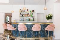 a bar with pink stools in front of a counter at La Bastide Bourrelly - Mathias Dandine in Cabriès