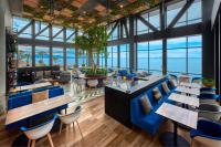a restaurant with blue chairs and tables and the ocean at City Express Plus by Marriott Ensenada in Ensenada