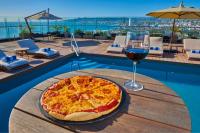 a pizza and a glass of wine on a table next to a pool at City Express Plus by Marriott Ensenada in Ensenada