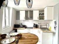 a kitchen with white cabinets and a wooden table at Appartement calme, plein-centre de Douai in Douai