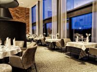 ein Restaurant mit Tischen und Stühlen und großen Fenstern in der Unterkunft Wellness & Naturresort Reischlhof in Wegscheid