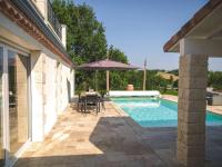 a patio with a table and an umbrella next to a swimming pool at Villa Maurine - Piscine chauffée - Spa - Clim - Salle de Fitness in Castelnau-de-Montmiral