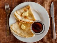 a plate of pancakes with butter and a cup of syrup at Pangani Cliffs Lodge in Pangani