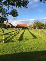 a fence on a grassy field with a barn at B&amp;B - Ter Douve in Dranouter