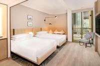 a hotel room with two beds and a chair at Sheraton Abu Dhabi Hotel & Resort in Abu Dhabi