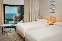 two beds in a hotel room with a view of the ocean at Sheraton Abu Dhabi Hotel & Resort in Abu Dhabi