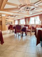 Un comedor con mesas y sillas y un techo en Hotel Panorama, en Passo del Tonale