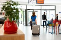 a woman walking through an airport with her luggage at UCPA SPORT STATION HOSTEL PARIS in Paris