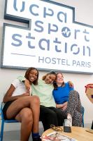 three women sitting on a chair in front of a sign at UCPA SPORT STATION HOSTEL PARIS in Paris