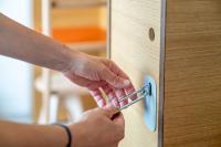 a person unlocking a wooden door with a key at UCPA SPORT STATION HOSTEL PARIS in Paris
