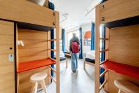 a man walking through a dorm room with bunk beds at UCPA SPORT STATION HOSTEL PARIS in Paris