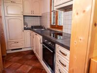 a kitchen with white cabinets and a black stove top oven at Alpin-Hütten auf der Turracherhöhe Haus Murmeltier by S4Y in Turracher Hohe