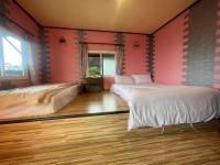 two beds in a room with pink walls and wooden floors at Emmanuel Farm House in Ren&#39;ai