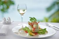 a plate of food on a table with a glass of wine at DoubleTree by Hilton Seychelles Allamanda Resort & Spa in Takamaka
