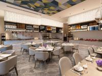 a restaurant with tables and chairs and a kitchen at Doubletree By Hilton Kunming Airport in Kunming