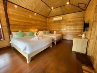 two beds in a room with wooden walls at Palm Leaf Resort Koh Tao in Ko Tao