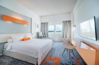 a hotel room with a bed and a desk and a television at HARRIS Hotel Batam Center in Batam Center