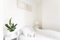 a white bedroom with a white bed and a plant at Luxury modern two bedroom duplex by Roland Garros in Paris