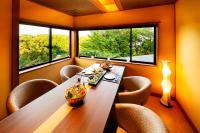 a dining room with a table and chairs and two windows at Noto Hyakurakusou in Ogi