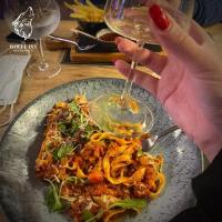 een persoon die een glas wijn vasthoudt naast een bord voedsel bij The Wolfe Inn Wolfscastle in Haverfordwest