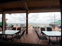 eine Terrasse mit Tischen und Stühlen und Blick auf das Wasser in der Unterkunft Resort Attractions in Willis