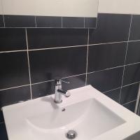 a white sink in a bathroom with black tiles at Appartement T2 Brest Pilier Rouge avec internet in Brest