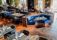 a restaurant with tables and a blue couch at Hilton The Hague in The Hague