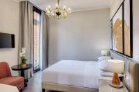 a white bedroom with a bed and a chair and a chandelier at Hilton Molino Stucky Venice in Venice