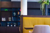 a yellow chair in a room with a book shelf at Hampton By Hilton Toulouse Airport in Blagnac