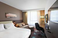 a hotel room with a large bed and a couch at Hampton By Hilton Toulouse Airport in Blagnac