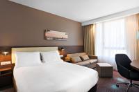 a hotel room with a large white bed and a chair at Hampton By Hilton Toulouse Airport in Blagnac