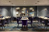 هيلتون دوسلدورف في دوسلدورف: غرفة طعام مع طاولات وكراسي وصور على الجدران