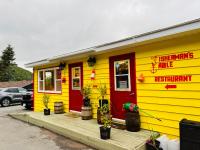 een geel gebouw met een rode deur en een restaurant bij Knotty Pine Cottages, Suites & Motel Rooms in Ingonish Beach