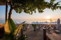 a boardwalk with chairs and a beach at sunset at Ostria Sea Side Hotel in Hanioti