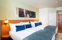 two beds in a hotel room with blue pillows at Leonardo Hotel Salzburg Airport in Salzburg