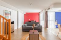 a living room with a couch and a red wall at Appart&#39;City Confort Pau Centre in Pau