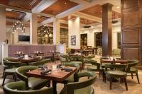 Un restaurante con mesas de madera y sillas verdes. en Hilton Garden Inn Memphis Downtown Beale Street, en Memphis