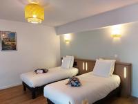 two beds in a hotel room with white sheets at Appart&#39;City Confort Pau Centre in Pau