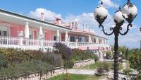 Un gran edificio rosa y blanco con una farola. en Hotel Villa Sevasti, en Katerini